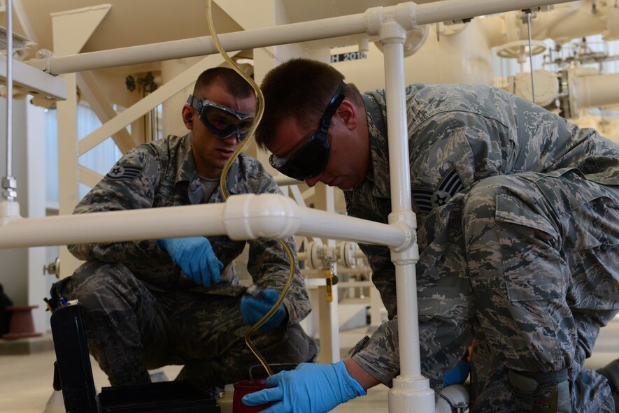 Staff Sgts. Derek Mclemore, left, and Jermey Manning, 2nd Logistics Readiness Squadron fuels laboratory technicians, collect fuel in a reservoir at Barksdale Air Force Base, La., Oct. 14, 2015. The fuel will be tested for particle and water content to make sure the highest quality of fuel is available. (Air Force Photo/Airman 1st Class Luke Hill)
