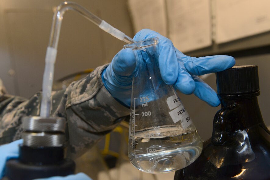 Staff Sgt. Derek Mclemore, 2nd Logistics Readiness Squadron fuels laboratory technician, fills a bottle with ether in order to clean items that were used during the fuel test in the fuel laboratory at Barksdale Air Force Base, La., Oct. 14, 2015. All equipment must be cleaned to ensure that residue from past tests does not alter future results. (U.S. Air Force Photo/Airman 1st Class Luke Hill)