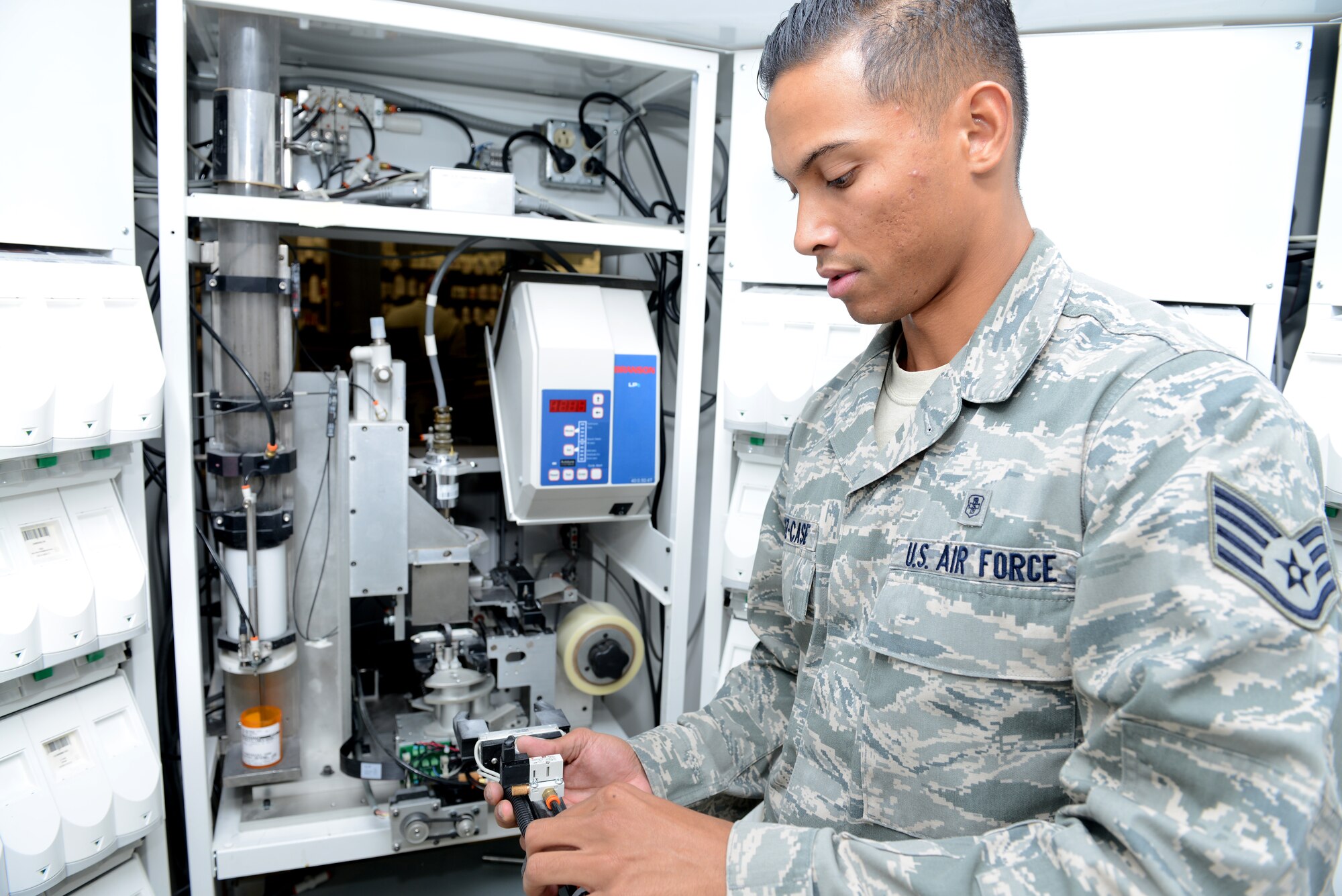 Staff Sgt. Aaron Munoz-Case, 56th Medical Support Squadron Arizona Refilling Center acting NCO in charge, adjusts the robotic arm at Luke Air Force Base, Arizona, Oct. 19, 2015. The robotic arm system helps Airmen at the ARC refill approximately 60 percent of all prescriptions. (U.S. Air Force photo by Senior Airman James Hensley)