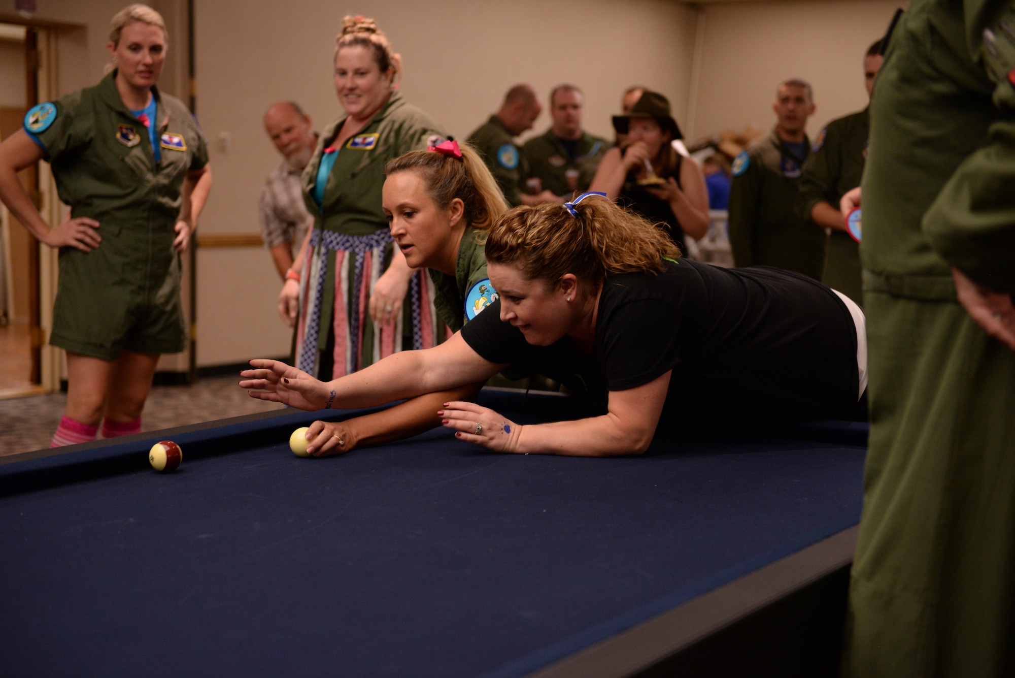 Members from two opposing teams struggle for domination of the billiards table during the annual Ladies’ Crud tournament, Oct. 16, 2015 at Luke Air Force Base. The tournament holds a long history and heritage at Luke, originating in fighter pilot culture before transitioning to an activity among their wives also.