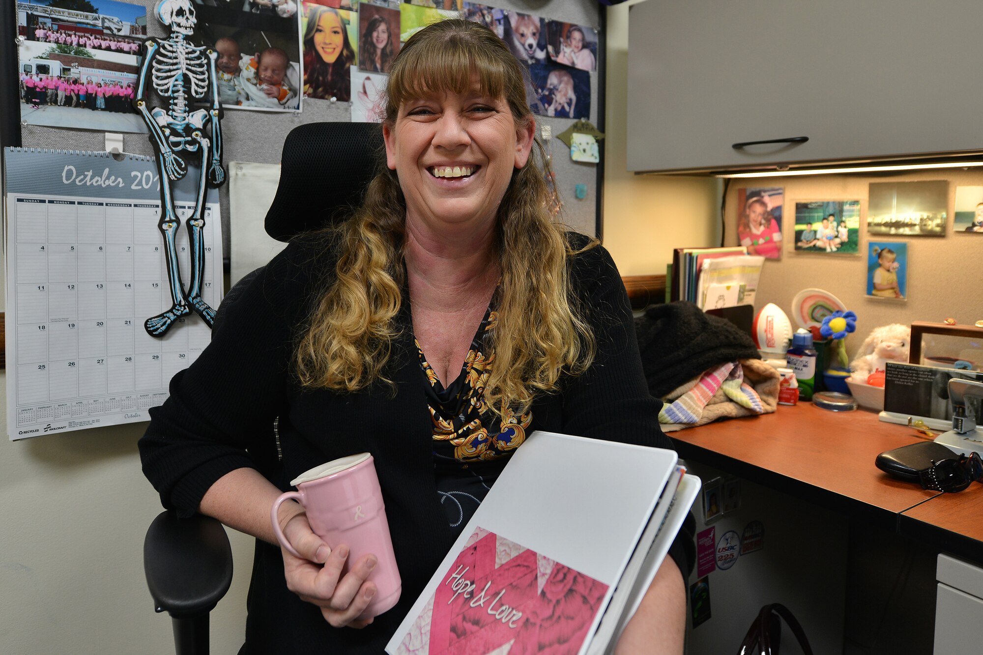 Donna Haynes, 733rd Civil Engineer Division environmental programs assistant, holds breast cancer awareness items at her desk at Fort Eustis, Va., Oct. 19, 2015. Haynes was diagnosed with breast cancer Sept. 24, 2015, and advocates the importance of receiving mammograms, as the checkup found the 8 millimeter sized cancerous tumor in her breast. (U.S. Air Force photo by Staff Sgt. Natasha Stannard/Released)
