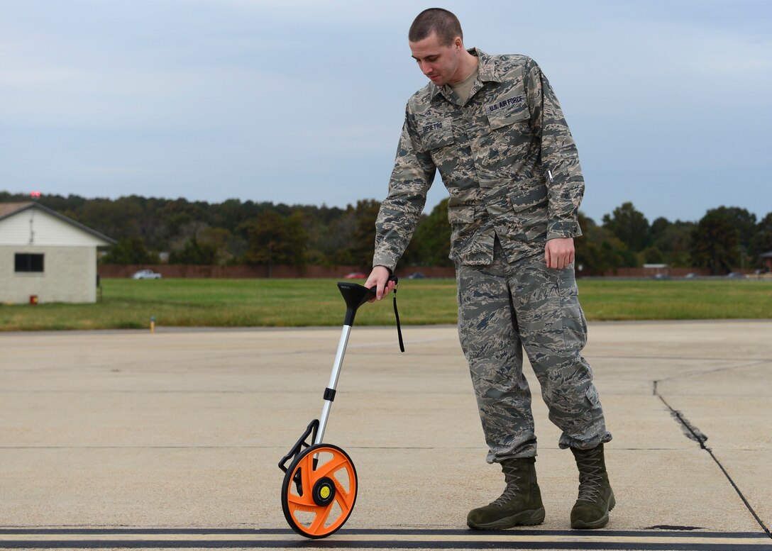 U.S. Air Force Senior Airman Jon Dipietro, 1st Operations Support Squadron Airfield Management shift lead, measures lines for proper width on the flight line at Langley Air Force Base, Va., Oct. 16, 2015. The distance between the painted lines and markers determines the path an aircraft is approved for. (U.S. Air Force photo by Airman 1st Class Derek Seifert/ Released)