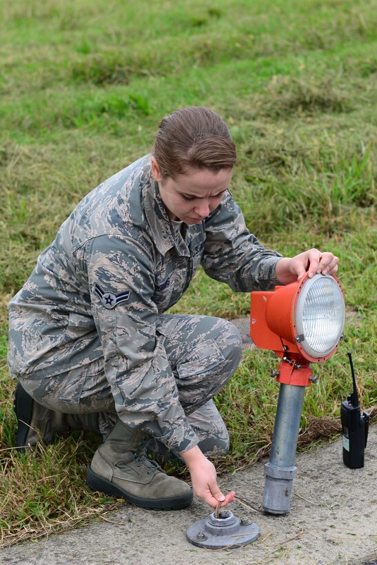 U.S. Air Force Airman 1st Class Alison Coombs, 1st Operations Support Squadron Airfield Management shift lead, examines a broken light fixture on the flight line at Langley Air Force Base, Va., Oct. 16, 2015. Airfield management specialists inspect the flight line and remove hazardous materials that may damage jets. (U.S. Air Force photo by Airman 1st Class Derek Seifert/ Released)