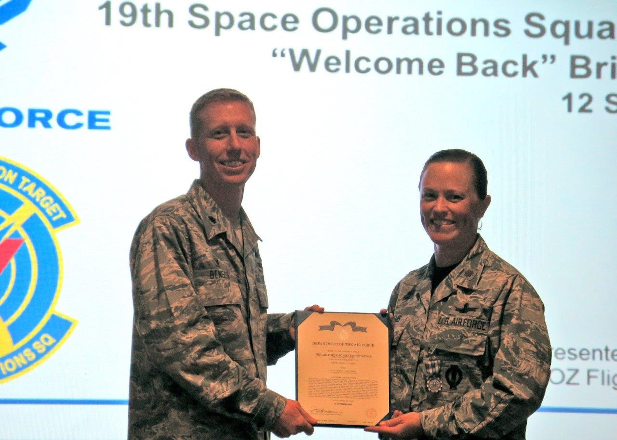 Lt. Col. Todd Benson, 2nd Space Operations Squadron commander, presents the Air Force Achievement Medal and citation to Maj. Kimberly Adams, 19th Space Operations Squadron Operations Flight commander during a Reserve Unit Training Assembly weekend Sept. 12, 2015 in the Building 300 auditorium at Schriever Air Force Base, Colorado. The medal was a complete surprise and was presented in front of the entire squadron and 310th Space Wing leadership, including the wing and group commanders. (Courtesy photo)