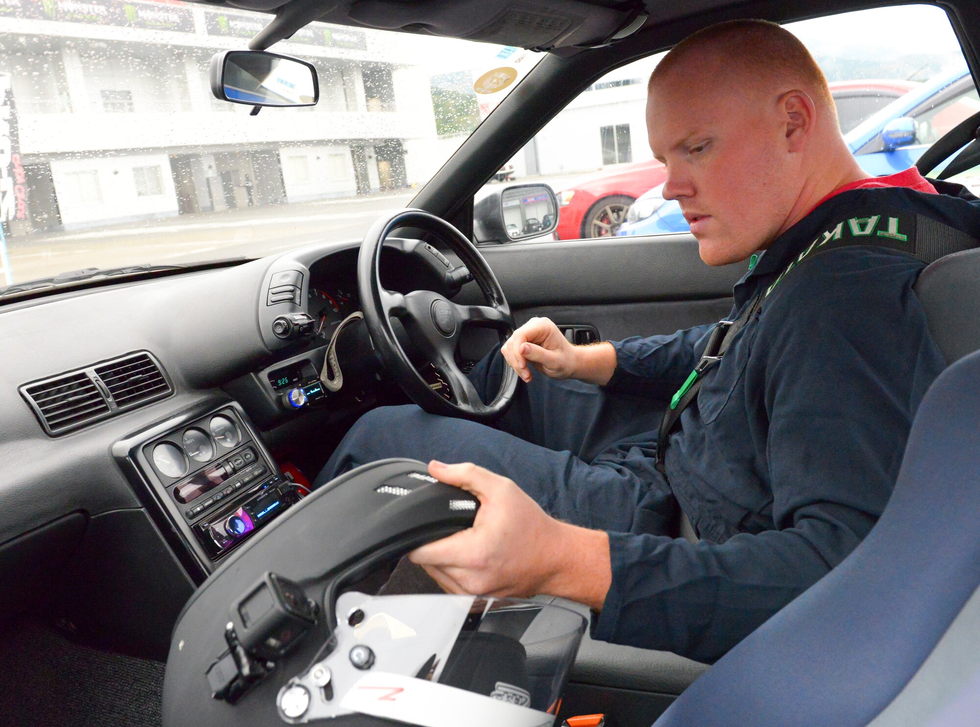 Senior Airman Thomas Kirts, 374th Civil Engineer Squadron driver operator, prepares to put on his helmet before entering the track at Fuji Speedway, Japan, Oct. 17, 2015. Kirts races during his off time to experience the adrenaline that comes with high speeds. (U.S. Air Force photo by Airman 1st Class Elizabeth Baker/Released)