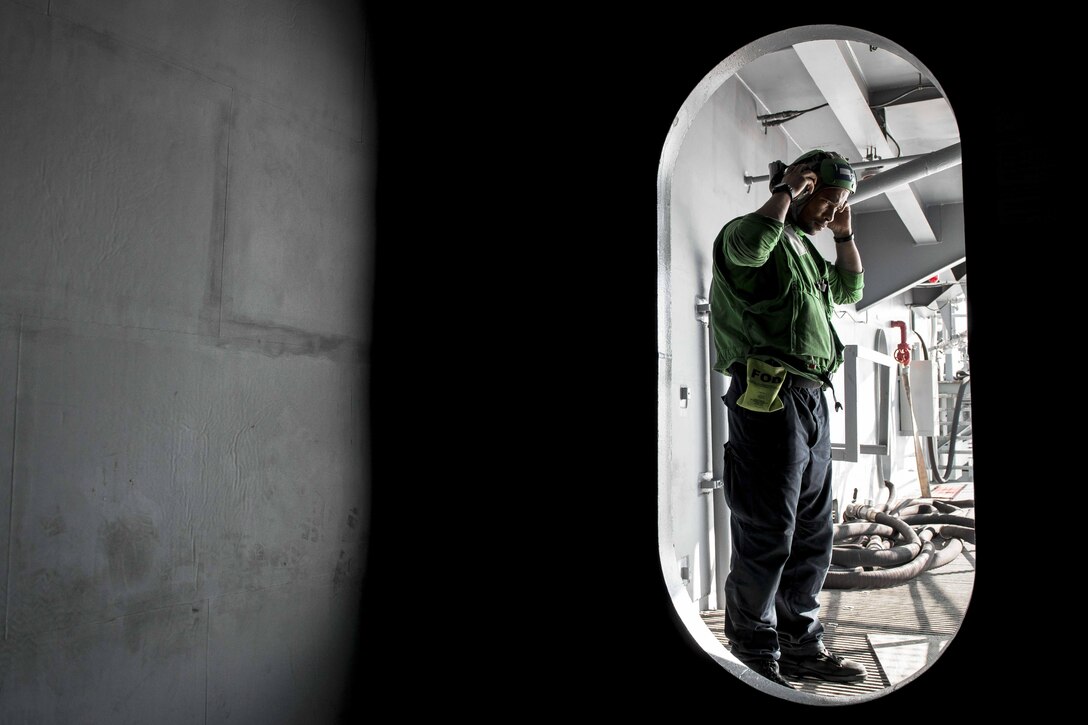 Petty Officer 3rd Class Xavier Smith dons a cloth-helmet assembly before entering the flight deck of the USS Ronald Reagan in waters south of Japan, Oct. 19, 2015. Smith is an aviation electronics technician assigned to Strike Fighter Squadron 102. U.S. Navy photo by Petty Officer 3rd Class Ryan McFarlane