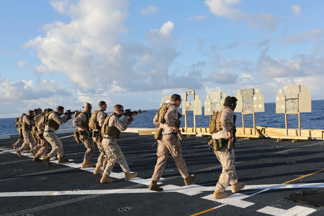 U.S. Marines prepare to fire while walking toward stationary targets during a deck shoot aboard the USS Arlington in the Atlantic Ocean, Oct. 12, 2015. U.S. Marine Corps photo by Cpl. Jeraco Jenkins