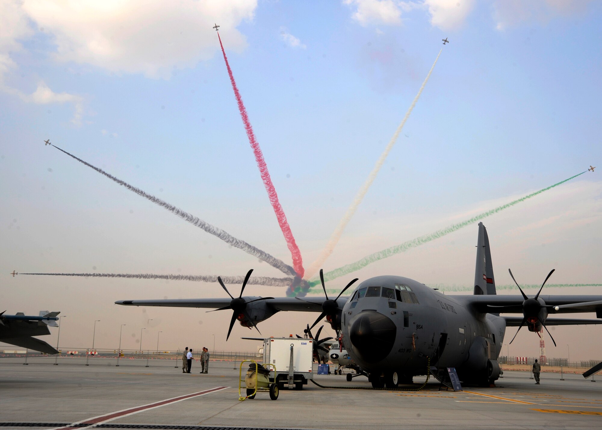 The United Arab Emirates air force display team, Al Fursan, performs an aerial demonstration pictured behind a U.S. Air Force C-130J Hercules during the 2013 Dubai Airshow at the Dubai World Central Airport in Jebel Ali, United Arab Emirates, Nov. 20, 2013. The United States participates in the Dubai Air Show to demonstrate a commitment to regional security, to demonstrate the flexibility of airpower, and to strengthen military-to-military relationships with regional partners. The C-130J is deployed from Keesler Air Force Base, Miss.