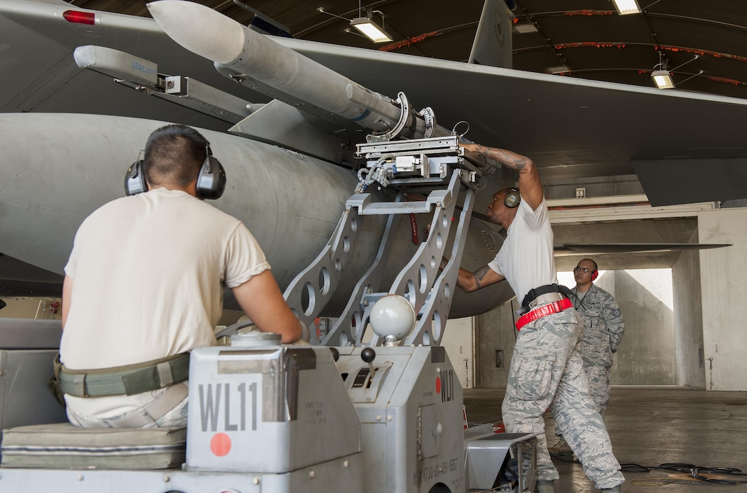 U.S. Air Force Staff Sgt. Craig Harrison, center, secures a LAU-128 missile with Airman 1st Class Brandon Myers during a weapons loading competition on Kadena Air Base, Japan, Oct. 19, 2015. Harrison is a weapons load crew chief and Myers is a weapons load crew member are assigned to 67th Fighter Squadron. U.S. Air Force photo by Airman Zackary A. Henry