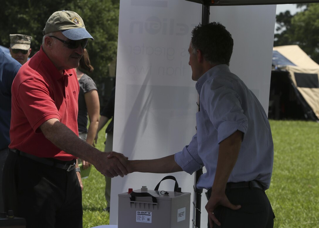 Retired Vice Adm. Dennis McGinn (left), the Assistant Secretary of the Navy for Energy, Installations and Environment, speaks to a representative of one of the civilian companies responsible for developing new, more energy efficient batteries for the Marine Corps at the Expeditionary Energy Concepts demonstration aboard Camp Lejeune, N.C., June 24, 2015. The demonstration drew VIPs from Marine Corps, Department of Defense and civilian organizations, as well as members of other military services and other countries.