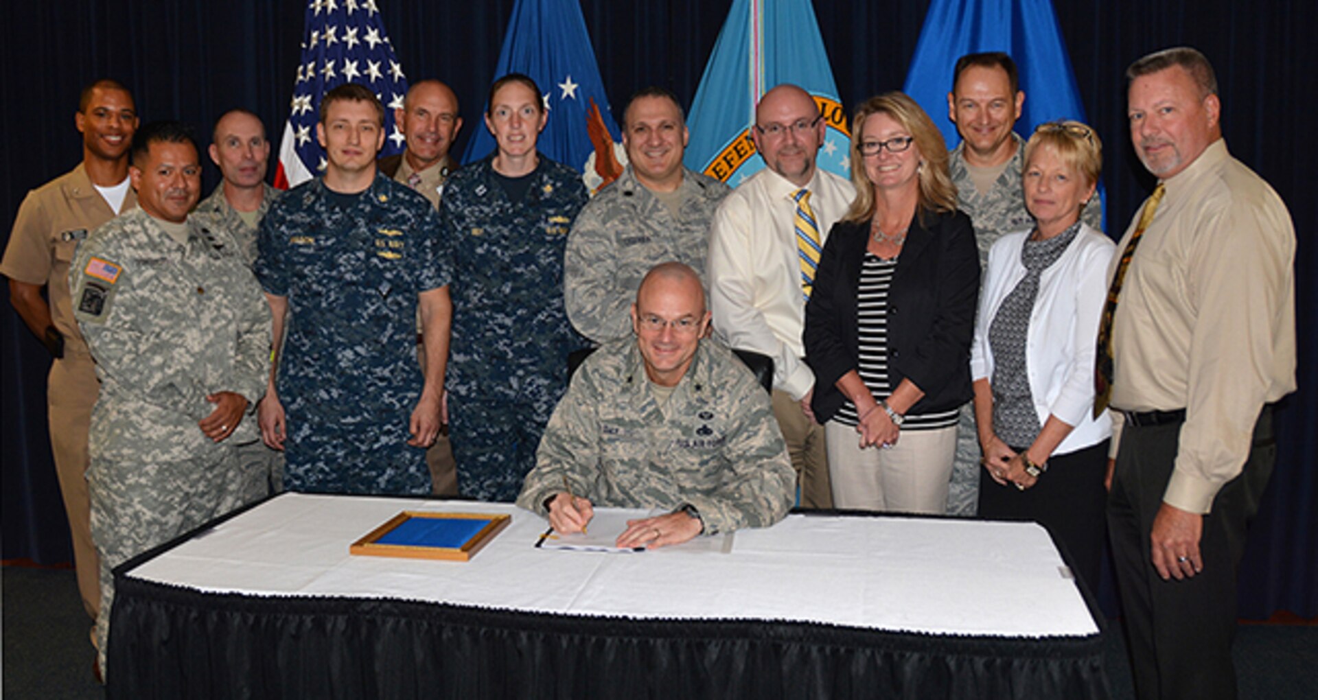 Defense Logistics Agency Aviation team members pose with DLA Aviation Commander Air Force Brig. Gen. Allan Day Sept. 17, 2015 in the commander’s conference room on Defense Supply Center Richmond, Virginia, as he signs volume one of the agency’s retail supply manual. The manual, began 22 months ago, outlines day-to-day operational procedures designed to provide supply excellence for Air Force retail operations.
