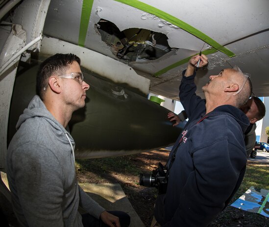 Senior Airman Sean Locklear, 437th Maintenance Squadron sheet metal technician, watches as Senior Master Sgt. Eric McKenzie, 437th MXS fabrication flight chief, marks points where to cut and drill an F-4 Phantom II Oct. 18, 2015, on the parade grounds at The Citadel in Charleston, S.C. During the recent storms that impacted the east coast, trees damaged the static aircraft. Parts of the wing, underwing and fuselage were severely compromised. The 437th AMXS volunteered weekends to assist the Citadel in repairing the aircraft the repairs. (U.S. Air Force photo/Airman 1st Class Clayton Cupit)