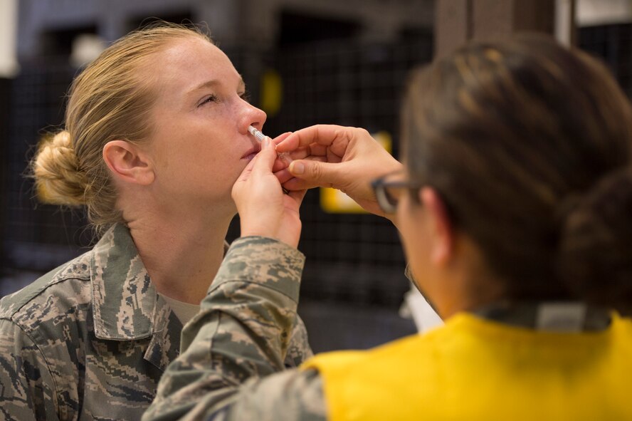 U.S. Air Force Tech. Sgt. Denise Streit, 52nd Civil Engineer Squadron emergency management, is administered the flu mist by U.S. Air Force Master Sgt. Angela Haston, 52nd Medical Operations Squadron primary care flight chief, during a disease containment plan exercise Oct. 21, 2015, at Spangdahlem Air Base, Germany. The vaccine must be stored between 2 and 8 degrees Celsius and only allowed to be out of that temperature once in its lifetime before use. (U.S. Air Force photo by Staff Sgt. Christopher Ruano/Released)