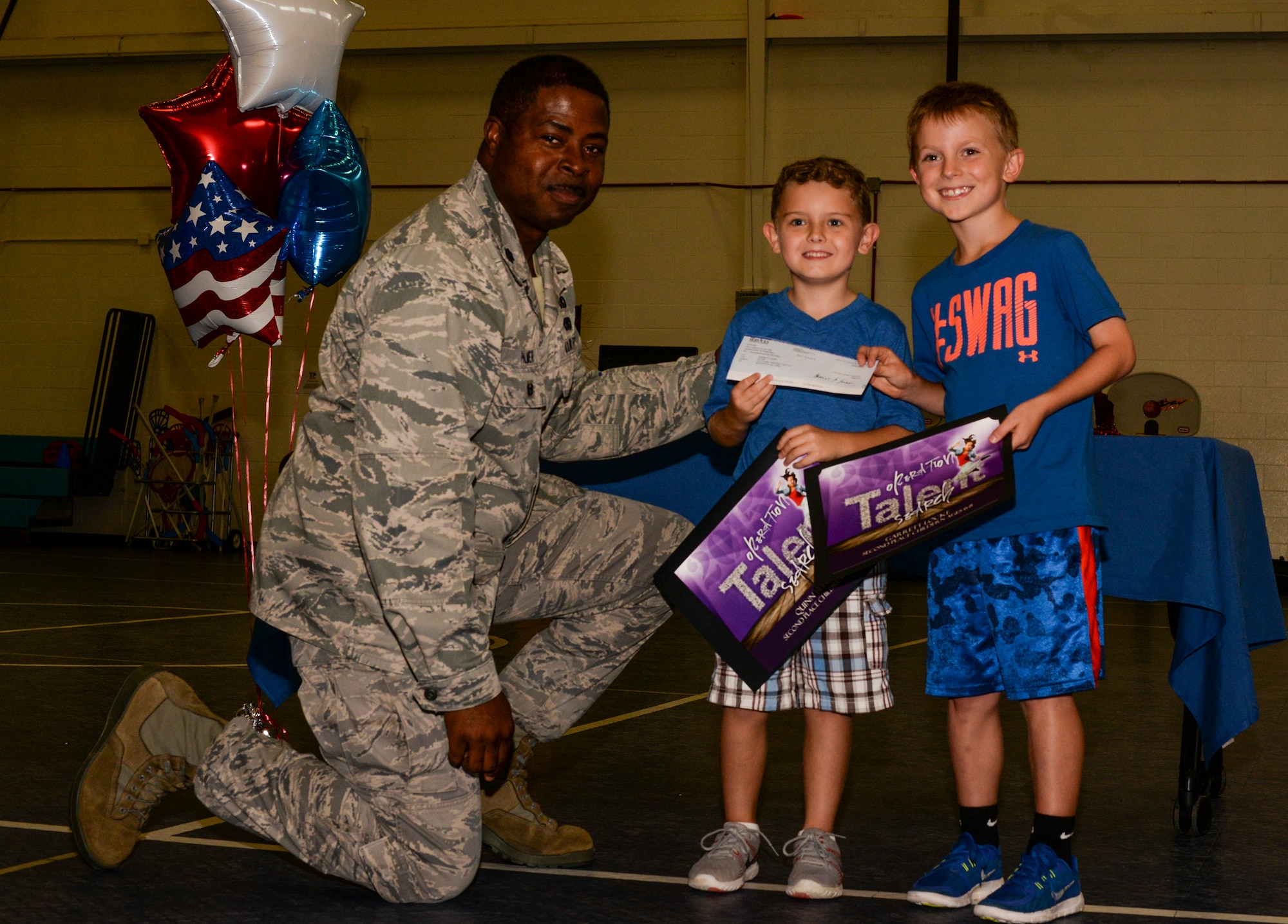 U.S. Air Force Lt. Col. Nathan Palmer, 23d Mission Support Group deputy commander, poses with Quinn Burgess, son of Tech. Sgt. Daniel Burgess, 41st Helicopter Maintenance Unit assistant section chief, and Garrett Locke, son of Col. Joseph Locke, 93d Air Ground Operations Wing commander, after presenting them with award certificates and a check for $200, September 9, 2015, at Moody Air Force Base Ga. Quinn, Garrett, and Devinn Dunn son of retired Master Sgt. James Dunn, danced their way to first place in the Moody Talent Search and second place in the Air Force wide Operation Talent Search. (U.S. Air Force photo by Airman 1st Class Janiqua P. Robinson/Released)
