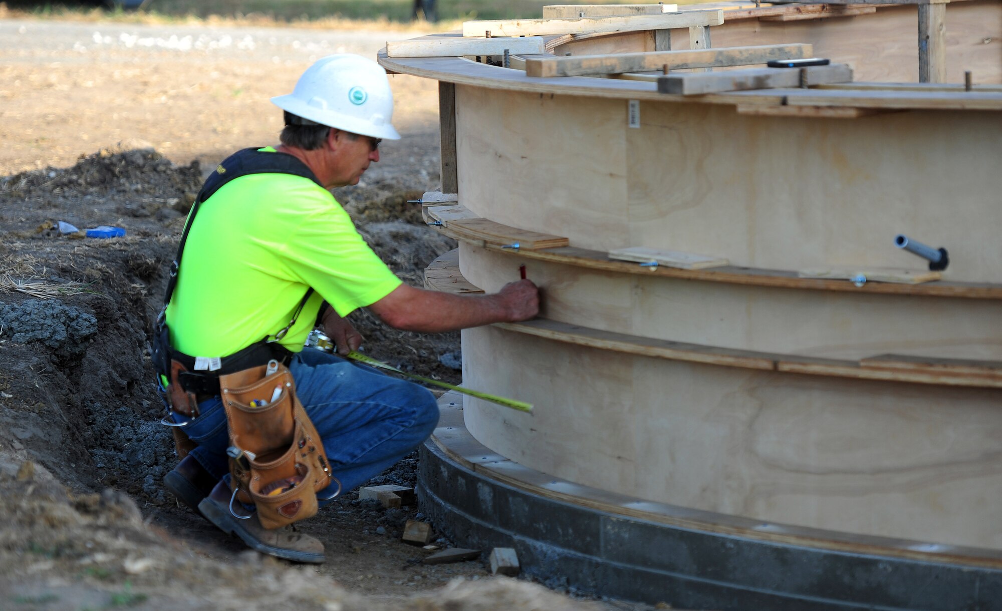 George Arney, a construction carpenter, marks drill holes in a new fire pit located near the Ike Skelton pavilion Oct. 21, 2015, at Whiteman Air Force Base, Mo. Form ties are inserted into the holes and used to prevent the structure from spreading when concrete is poured into the seating and supporting wall. The pavilion and stage area is scheduled to be closed until mid-December 2015. (U.S. Air Force photo by Airman 1st Class Jazmin Smith/Released)