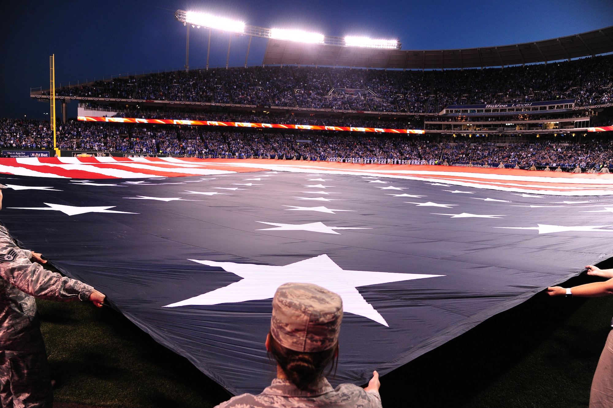 Members of Team Whiteman take part in a flag ceremony during the pregame ceremonies of the American League Championship Series at Kauffman Stadium in Kansas City, Mo., Oct. 16, 2015. More than 100 service members participated in the flag ceremony which was accompanied by a B-2 Spirit flyover. (U.S. Air Force photo by Senior Airman Joel Pfiester/Released)
