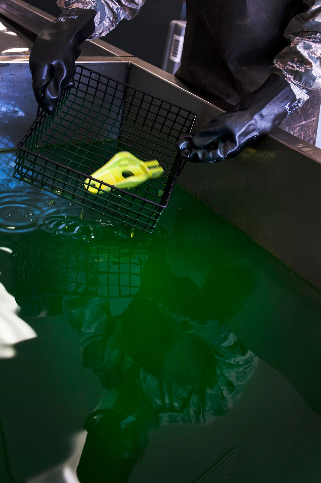 Airman 1st Class Joshua Fernandez, a 19th Maintenance Squadron nondestructive inspection apprentice, dips a part into liquid penetrant Oct. 14, 2015, at Little Rock Air Force Base, Ark. After the process the part will be put under a black light to check for cracks or defects. (U.S. Air Force photo by Senior Airman Stephanie Serrano)