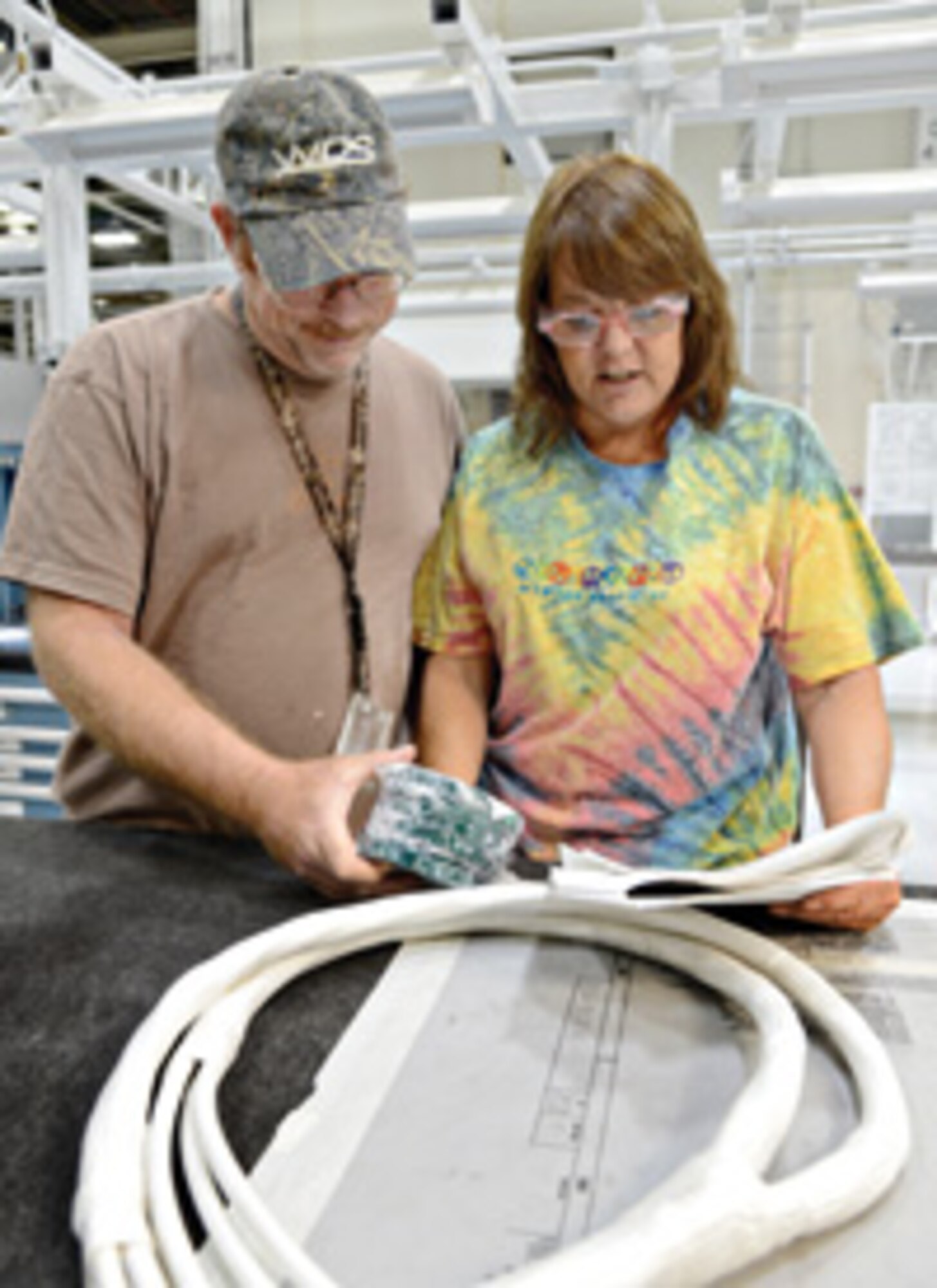 Jaime Olson, left, and Mark Norrell work together to build a prototype B-2 silver cable harness using a braiding machine in the 552nd Commodities Maintenance Squadron’s cable harness shop. By braiding the harness around the inner cables to secure them, it helps protect against vibrations, abrasions and moisture. Air Force photo by Kelly White/Released