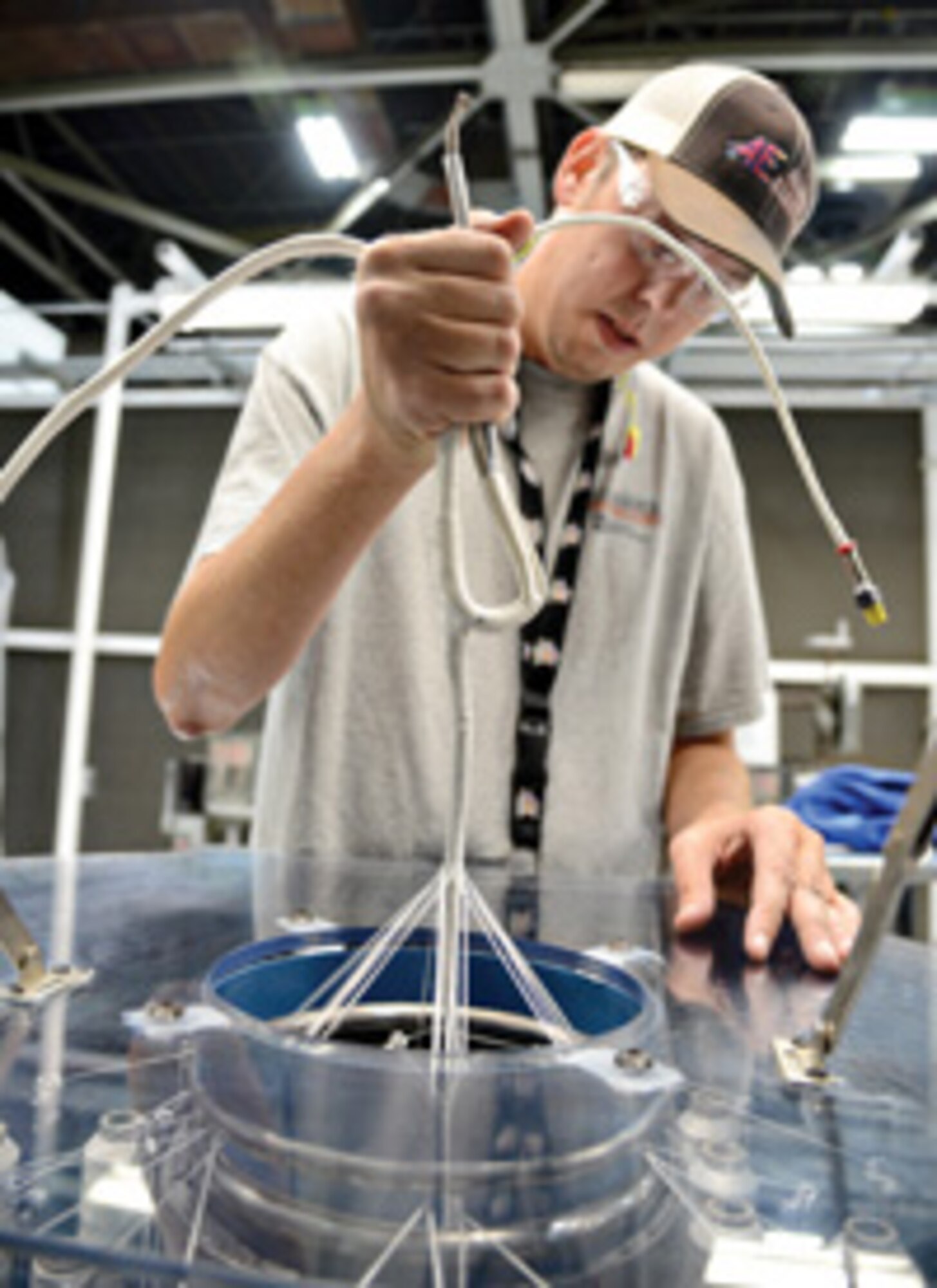 Jason Rosenfelt, an electrical equipment repairer with the 552nd Commodities Maintenance Group’s cable harness shop, uses a braiding machine to build an E3 fire loop with nickel-plated copper cable.  Air Force photo by Kelly White/Released