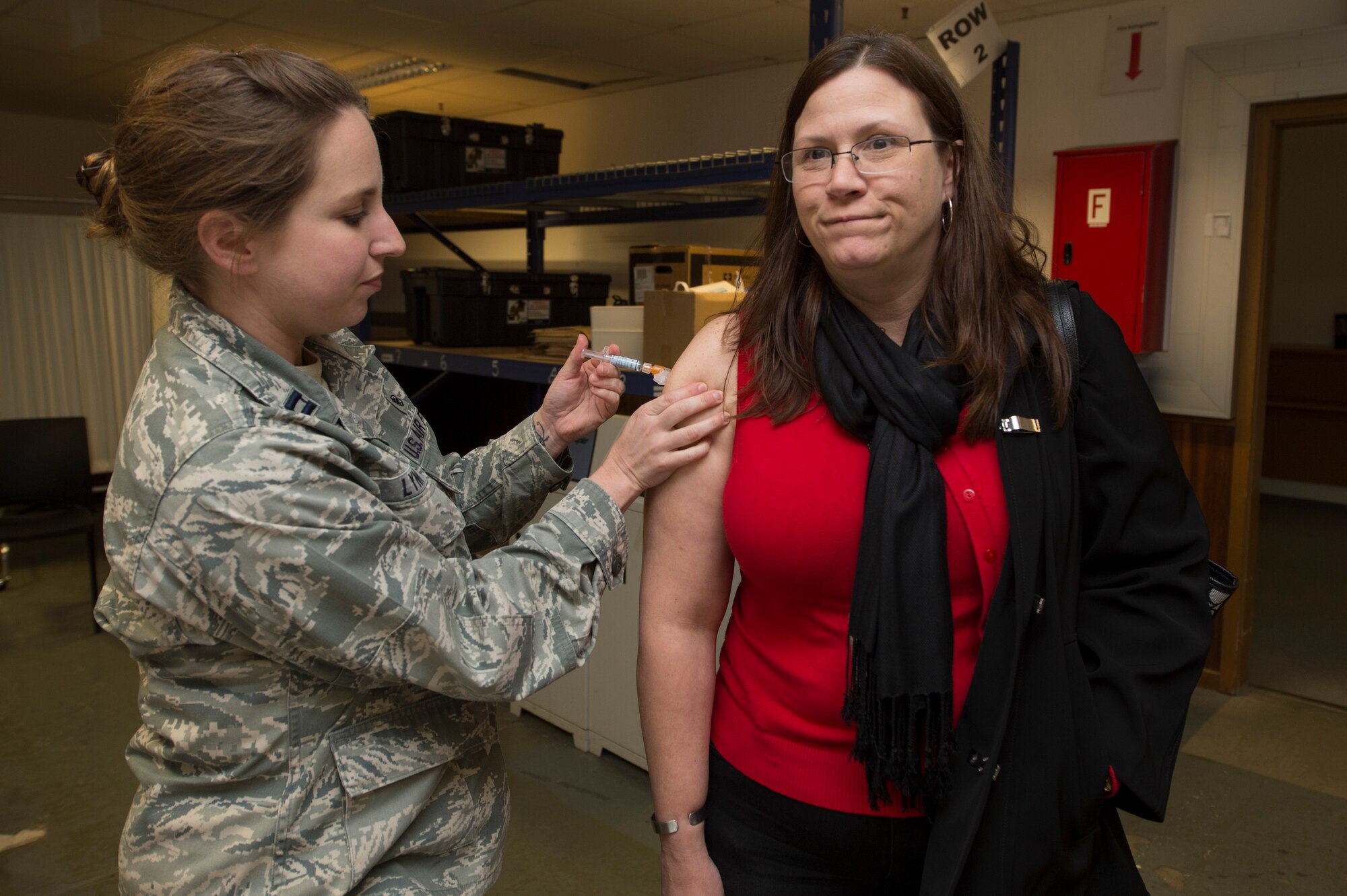 Patty McCormick, wife of U.S. Air Force Master Sgt. Michael McCormick, 726th Air Mobility Squadron quality assurance superintendent, is administered her flu shot by U.S. Air Force Capt. Amy Lynn, 52nd Medical Operations Squadron women’s health clinic element leader, during a disease containment plan exercise Oct. 21, 2015, at Spangdahlem Air Base, Germany. Common side effects for the injected vaccine include soreness, redness or swelling where the shot was received, fever, aches or cough. (U.S. Air Force photo by Staff Sgt. Christopher Ruano/Released)