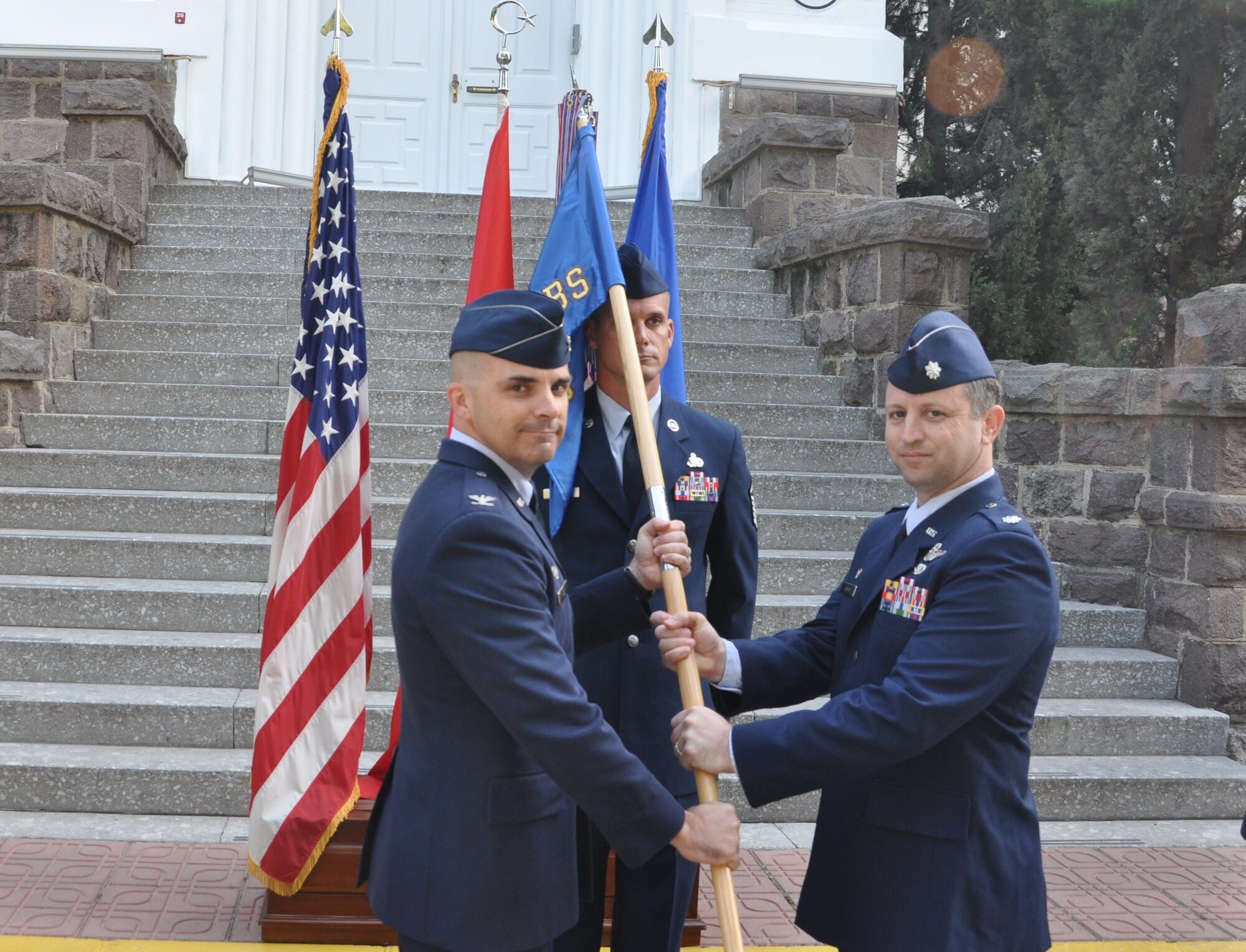 Col. Russell Voce, 39th Mission Support Group commander, left, accepts the guidon from Lt. Col. John Thomas, outgoing 425th Air Base Squadron commander, as he relinquishes command of the 425th ABS during a change of command ceremony Oct. 20, 2015, at Izmir Air Station, Turkey. Voce officiated the ceremony. (U.S. Air Force photo by Tanju Varlikli/Released)