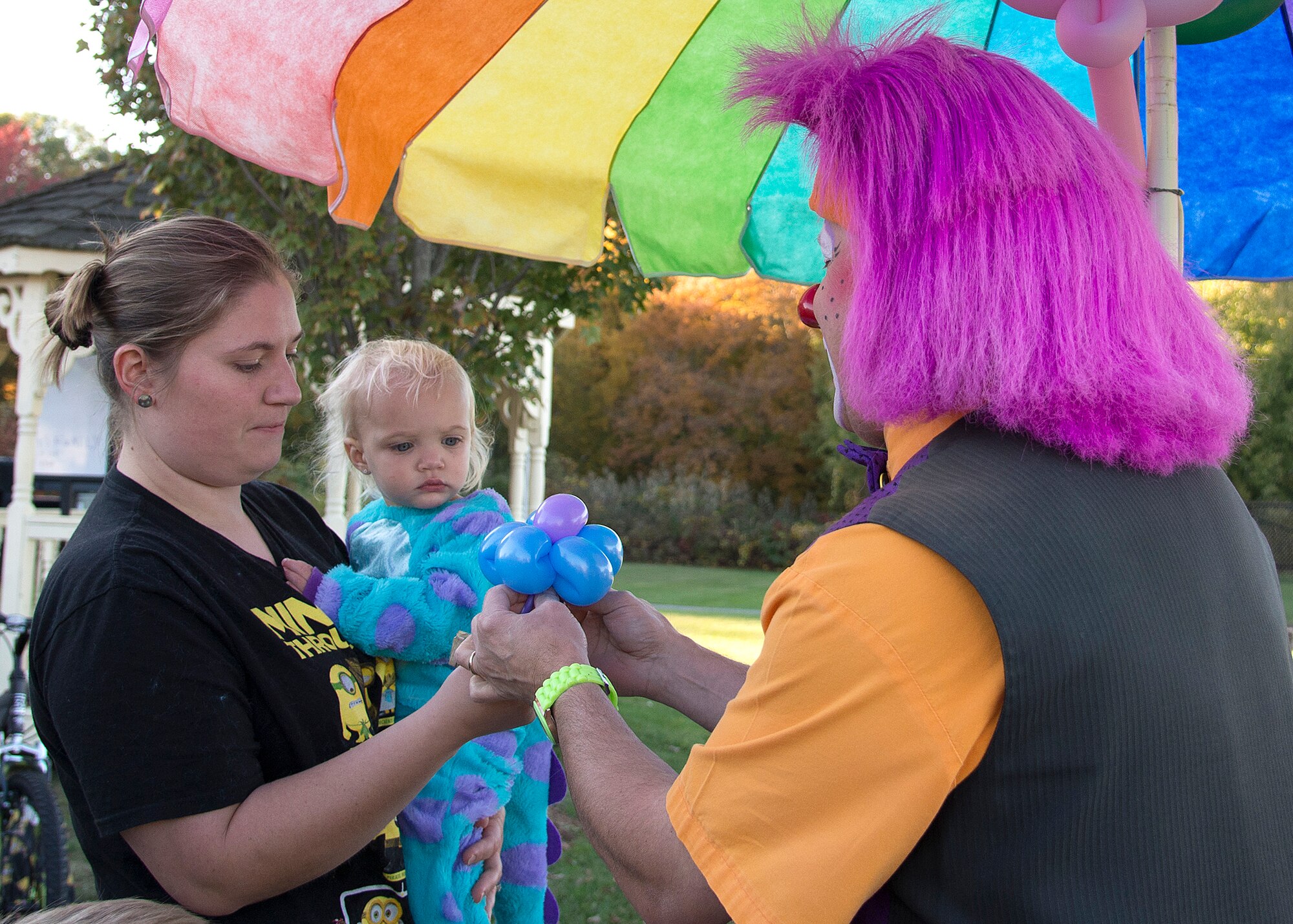 Silly Willy the Clown gives a balloon animal to Holly Courage, and her daughter, Annabelle, at the Hanscom Family Housing Fall Festival on base Oct. 16. The free event was held for housing residents. (U.S. Air Force photo by Walter Santos)