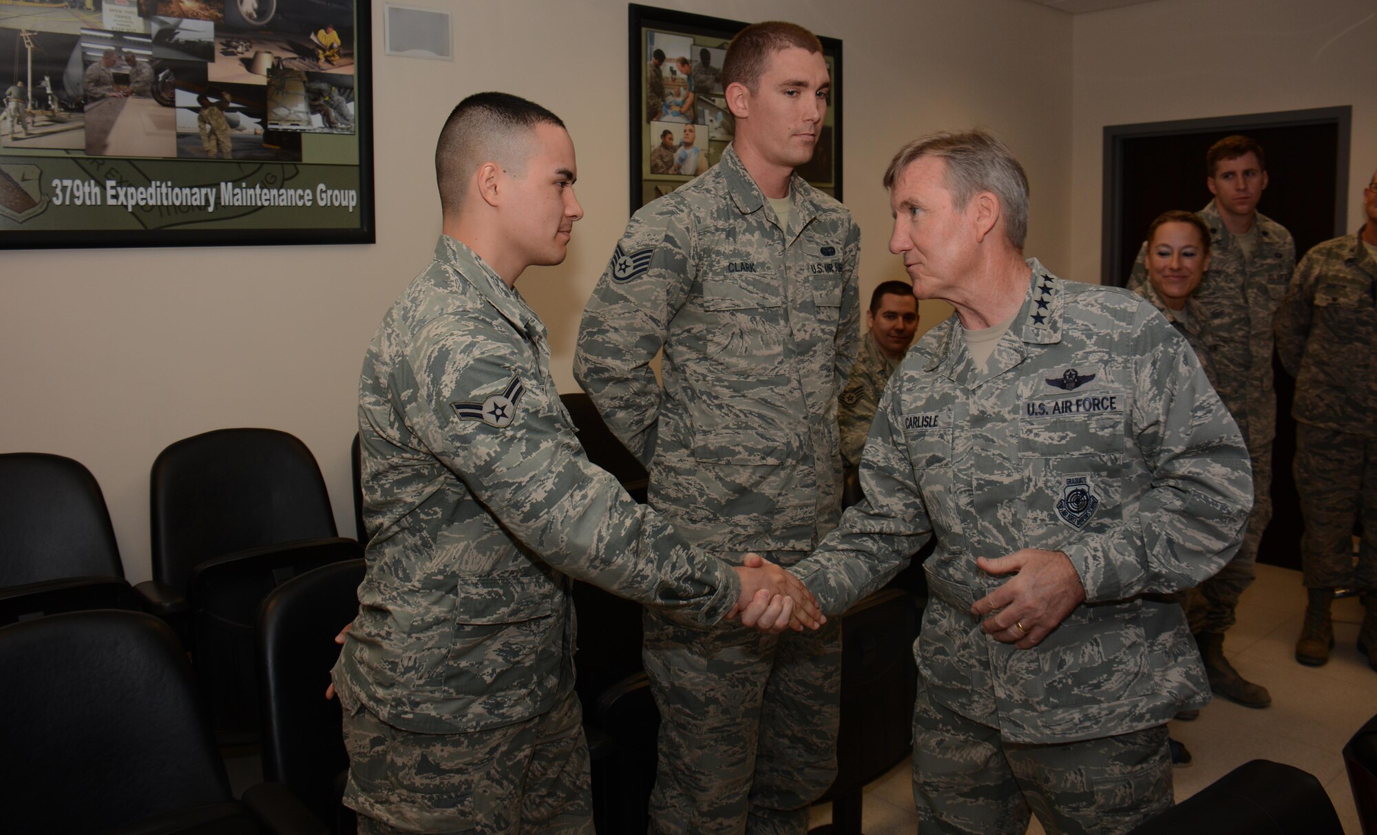U.S. Air Force Gen. Hawk Carlisle, commander of Air Combat Command, presents a coin to Airman 1st Class John Belcher, 379th Expeditionary Communications Squadron, for outstanding performance inside the Wing Operations Center at Al Udeid Air Base, Qatar Oct. 21, 2015. During his visit, Carlisle also received a 379th Air Expeditionary Wing mission briefing and hosted an all-call event with more than 300 members of AUAB. (U.S. Air Force photo by Tech. Sgt. James Hodgman/Released)