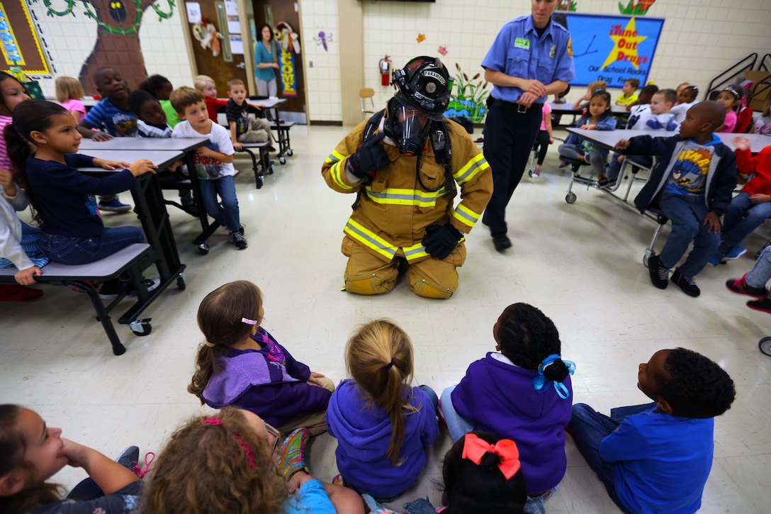 Robert Harrell demonstrates how firefighters interact with people in distress on emergencies during a visit to W. J. Gurganus Elementary School in Havelock, N.C., Oct. 22, 2015. Members of the Marine Corps Air Station Cherry Point Fire and Emergency Services Department visited the local elementary school to teach children about the importance of fire safety and prevention. The air station fire department actively participates in school visits to encourage children of all ages to practice safety measures to keep both their families and themselves safe. Harrell is a firefighting paramedic with the MCAS Cherry Point Fire and Emergency Services Department. (U.S. Marine Corps photo by Cpl. N.W. Huertas/Released)
