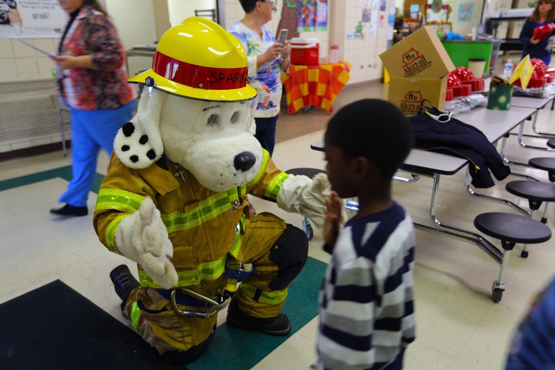 “Sparky the Fire Dog” greets a child during a visit to W. J. Gurganus Elementary School in Havelock, N.C., Oct. 22, 2015. Members of the Marine Corps Air Station Cherry Point Fire and Emergency Services Department visited the local elementary school to teach children about the importance of fire safety and prevention. The air station fire department actively participates in school visits to encourage children of all ages to practice safety measures to keep both their families and themselves safe. (U.S. Marine Corps photo by Cpl. N.W. Huertas/Released)