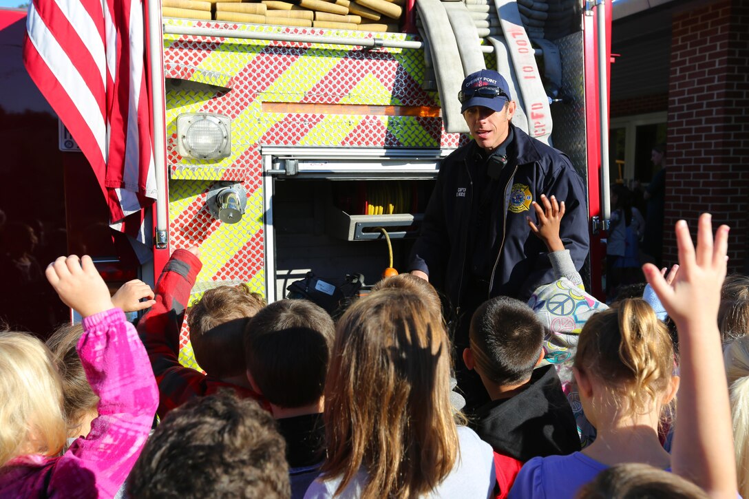 Capt. Eddie Hudson showcases gear used on a firetruck during a visit to W. J. Gurganus Elementary School in Havelock, N.C., Oct. 22, 2015. Members of the Marine Corps Air Station Cherry Point Fire and Emergency Services Department visited the local elementary school to teach children about the importance of fire safety and prevention. The air station fire department actively participates in school visits to encourage children of all ages to practice safety measures to keep both their families and themselves safe. Hudson is a fire captain with the MCAS Cherry Point Fire and Emergency Services Department. (U.S. Marine Corps photo by Cpl. N.W. Huertas/Released)