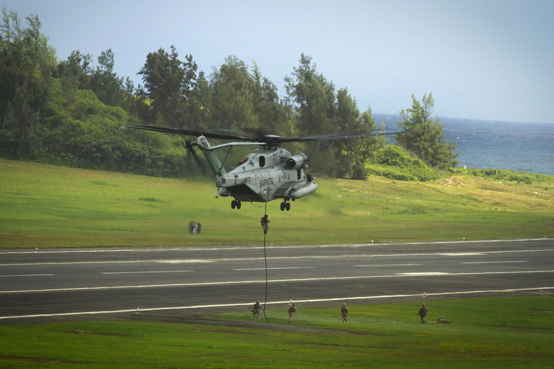 Marines fast-rope onto the tarmac from a CH-53E Super Stallion helicopter during an Air-Ground Task Force demonstration at the 2015 Kaneohe Bay Air Show on Marine Corps Air Station Kaneohe Bay in Hawaii, Oct. 17, 2015. The Marines are assigned to Alpha Company, 1st Battalion, 3rd Marine Regiment, 3D Marine Division. U.S. Marine Corps photo by Lance Cpl. Aaron S. Patterson  