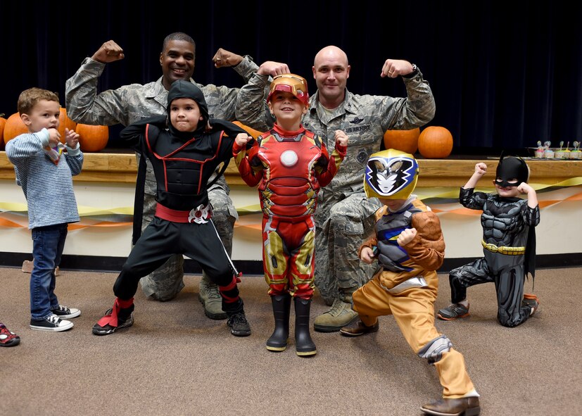 ALTUS AIR FORCE BASE, Okla. – U.S. Air Force Chief Master Sgt. James Powell, 97th Air Mobility Wing command chief and U.S. Air Force Col. Todd Hohn, 97th AMW commander, pose with children during a deployed family dinner at the Freedom Community Center, Oct. 22, 2015. The free dinner consisted of activities such as pumpkin carving, fishing, rubber duck racing, a bounce house and a costume contest for children to participate in. (U.S. Air Force photo by Senior Airman Franklin R. Ramos/Released)