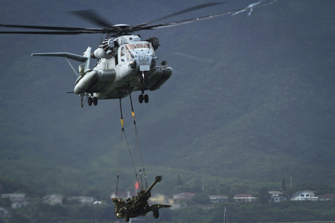 A U.S. Marine CH-53E Super Stallion helicopter lifts a howitzer as a part of an Air-Ground Task Force demonstration at the 2015 Kaneohe Bay Air Show on Marine Corps Air Station Kaneohe Bay in Hawaii, Oct. 17, 2015. The helicopter crew is assigned to Marine Heavy Helicopter Squadron 463. U.S. Marine Corps photo by Lance Cpl. Aaron S. Patterson