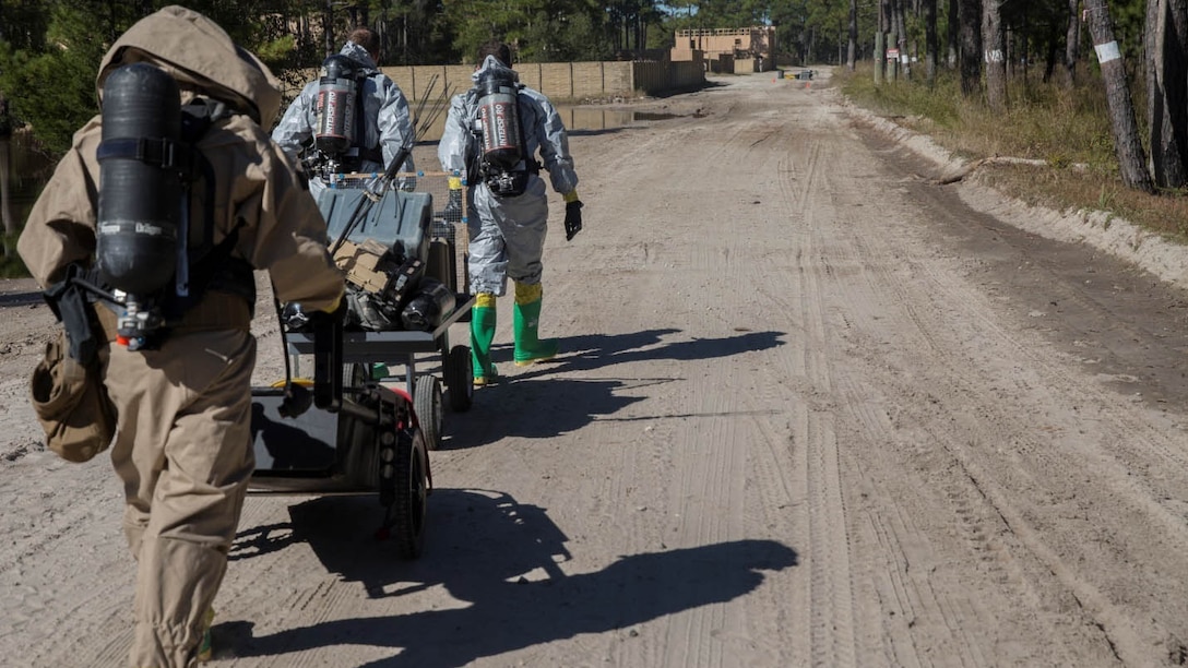 Marines from Explosive Ordnance Disposal Company, 8th Engineer Support Battalion and 2nd Chemical, Biological, Radiological, Nuclear Defense Detachment, transport gear required to set up a decontamination zone during a company field exercise at Marine corps Base Camp Lejeune, N.C., Oct. 21, 2015. EOD received a call regarding a simulated device that would spread a deadly nerve agent throughout a hotel if it wasn't disabled.