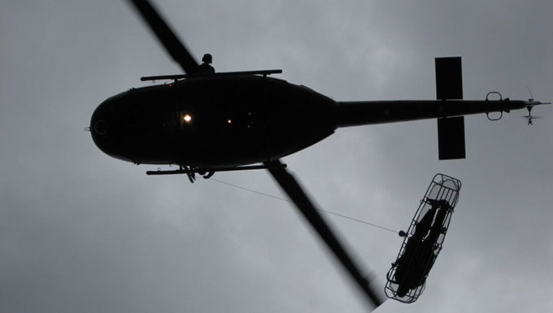 A “stokes litter” carrying an accident victim is hoisted up to a UH-1N Huey helicopter from the 40th Helicopter Squadron.  Once the patient is on board the aircraft, a flight surgeon or flight nurse can perform a life-saving role while en route to a local hospital or care facility for treatment. At Malmstrom, flight surgeons and flight nurses are required to accomplish one day and one night hoist per calendar year for training.  (U.S. Air Force photo/Capt. David Oettel)