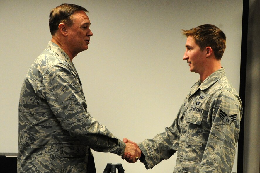 Air Force District of Washington Commander Maj. Gen. Darryl W. Burke coins SrA Drew Tesar, 11th Civil Engineer Squadron Explosive Ordnance Disposal craftsman, on Joint Base Andrews, Md., Oct. 23, 2015. Burke communicates his appreciation for the EOD Airmen’s sacrifice for the mission and recognized excellence within their career field. (U.S. Air Force photo/Staff Sgt. Matt Davis)