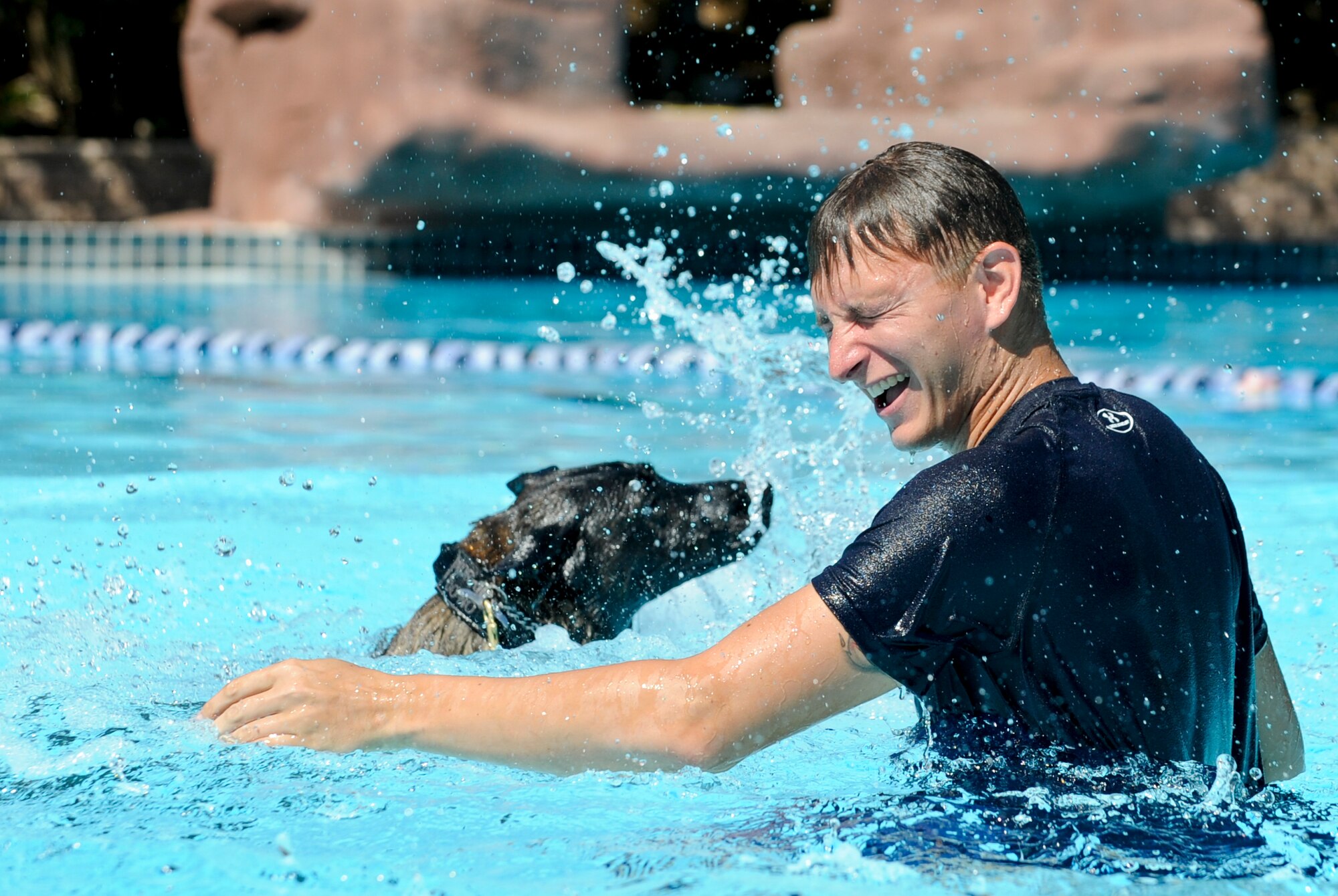 Staff Sgt. Jenings Casey, 6th Security Forces Squadron military working dog handler, and MWD Branco splash in a wave pool after a water aggression training exercise at a local water park in Tampa, Fla., Oct. 15, 2015. The water aggression training offers a unique opportunity for working dogs to become familiar with water. (U.S. Air Force photo by Airman 1st Class Mariette M. Adams/Released)