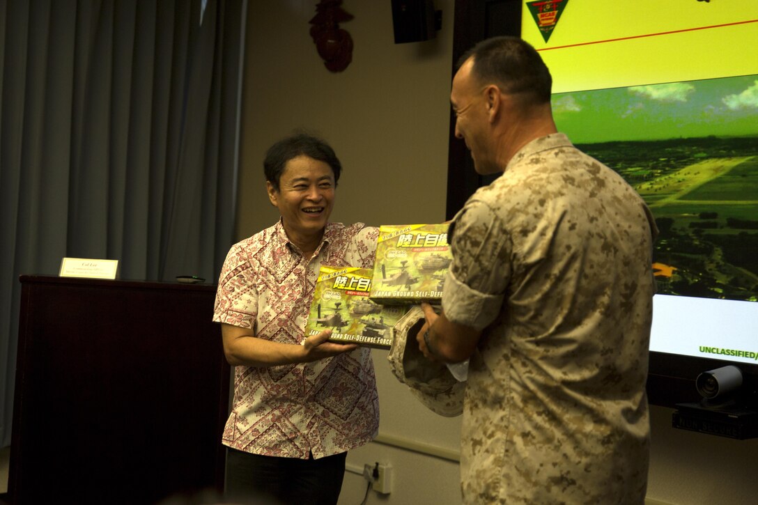 Asao Ogimi, left, presents gifts to Col. Peter Lee during an educational tour Oct. 22 on Marine Corps Air Station Futenma, Okinawa, Japan. During the tour, members of the Okinawa Prefecture Defense Association learned about the history and tenant commands of MCAS Futenma and their capabilities. After a question and answer session, the members boarded a bus for a windshield tour of the installation. Ogimi is a chairman with the Okinawa Prefecture Defense Association. Lee is the commanding officer of MCAS Futenma, Marine Corps Installations Pacific and a New Rochelle, N.Y., native.