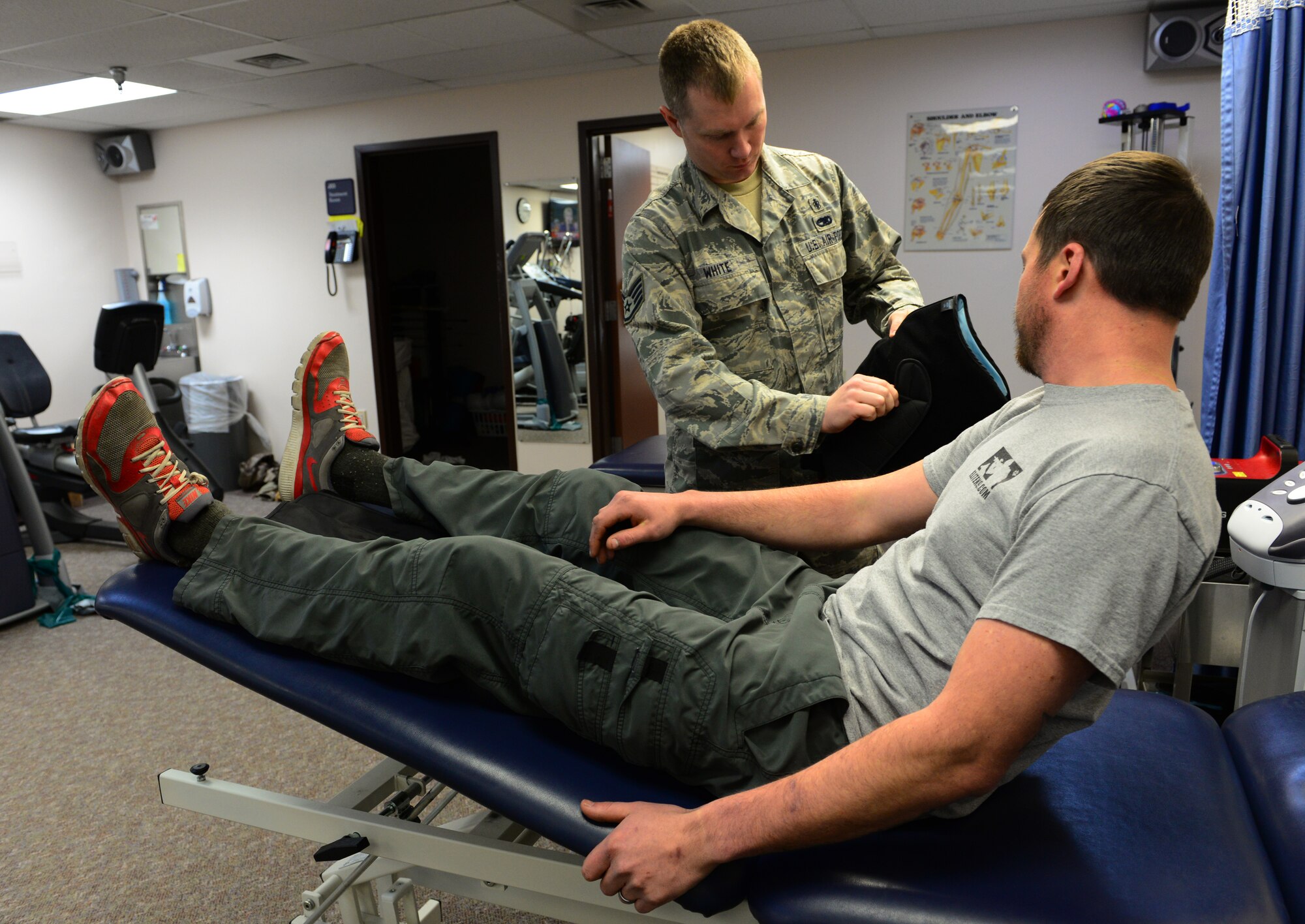 U.S. Air Force Staff Sgt. Michael White, a 354th Medical Group physical therapy technician, helps Staff Sgt. Barret Chappelle, a 354th Security Forces Squadron military working dog handler, put on the compression pack Oct. 22, 2015, at Eielson Air Force Base, Alaska. This helps alleviate pain after Chappelle’s physical therapy session by mixing compression with cold on the affected area. (U.S. Air Force photo by Airman 1st Class Cassandra Whitman/Released)