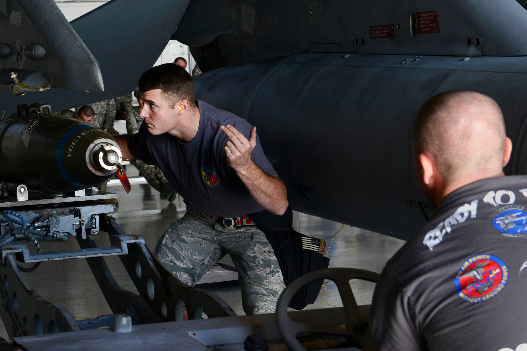 U.S. Air Force Staff Sgt. Benjamin Cooper, 20th Equipment Maintenance Squadron armament load crew chief, signals a weapon loader during a weapons load crew of the quarter competition at Shaw Air Force Base, S.C., Oct. 16, 2015. Load crews participating in the competition are evaluated on their dress and appearance standards as well as work ethic. (U.S. Air Force photo by Airman 1st Class Christopher Maldonado/Released)