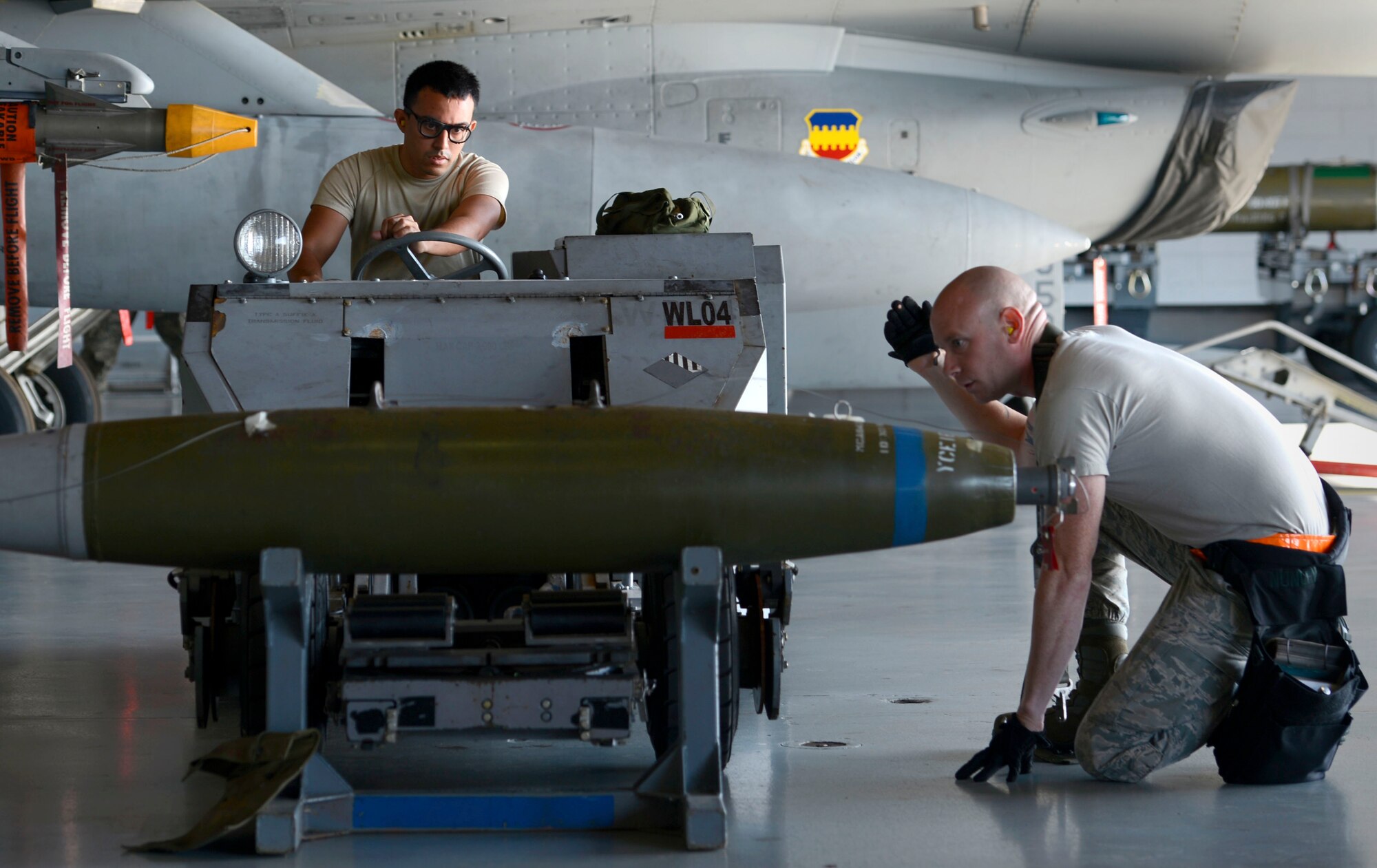 (From left) U.S. Air Force Airman 1st Class Jorge Maldonado, 20th Aircraft Maintenance Squadron, 79th Aircraft Maintenance Unit weapons load crew member, operates a weapon loader while signaled by Staff Sgt. Gregory Nunley, 20th AMXS, 79th AMU weapons load crew chief, during a weapons load crew of the quarter competition at Shaw Air Force Base, S.C., Oct. 16, 2015. The 79th AMU competed against the 77th AMU and 20th Equipment Maintenance Squadron load crew teams to determine who could load three types of munitions the fastest and most accurately. (U.S. Air Force photo by Senior Airman Jensen Stidham/Released)