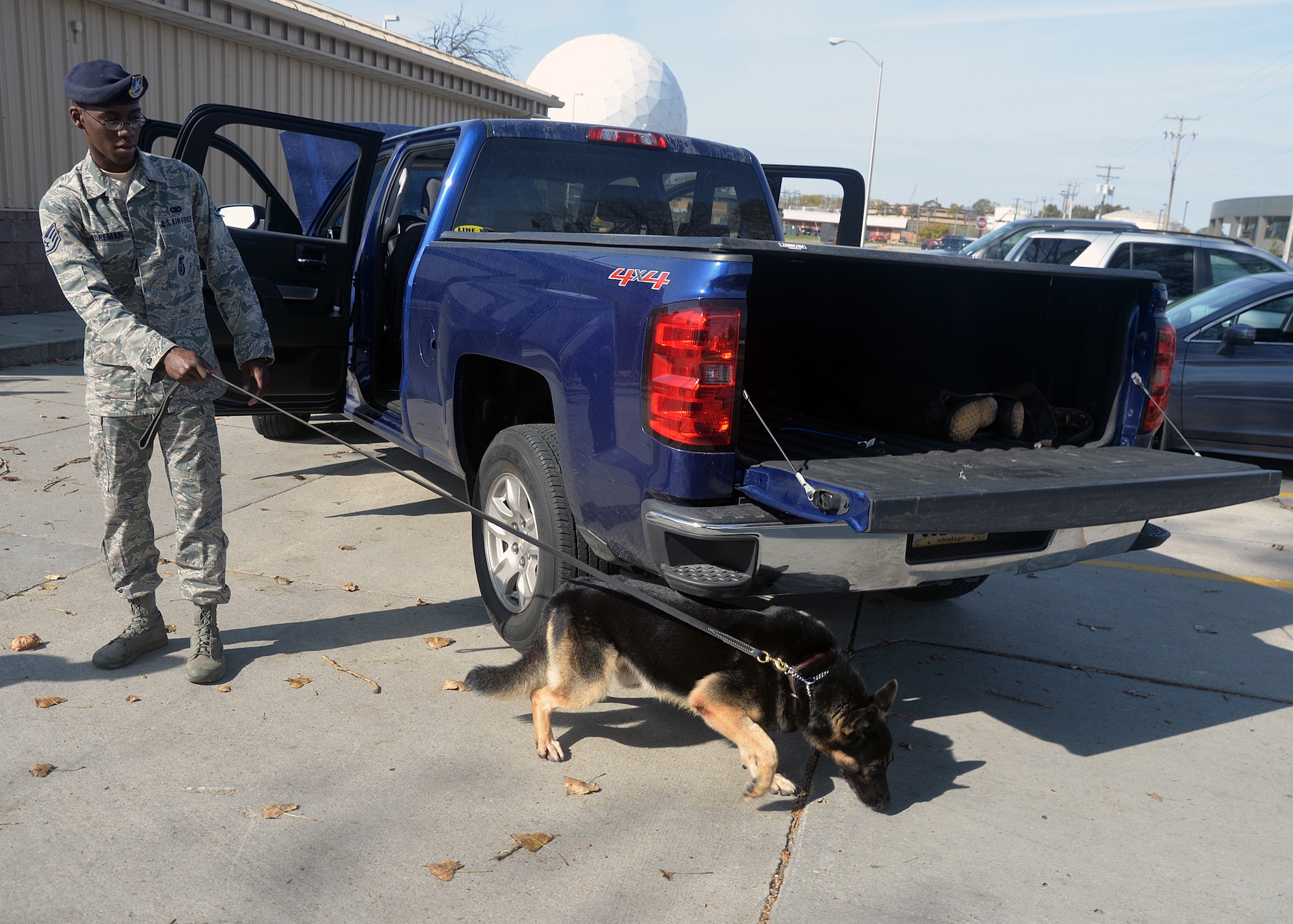 Staff Sgt. Elbert Foreman, 55th Security Force Squadron Military Working Dog handler, and Military Working Dog Rocky, perform a sweep around a vehicle Oct. 21 at the 55th SFS MWD training facility. MWD Rocky is validated in explosion detection. (U.S. Air Force photo by Kendra Williams/Released)