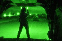 Airmen from the 60th Aerial Port Squadron and the Army National Guard's 49th Police Brigade practice loading and sling loading vehicles on a CH-47 Chinook cargo helicopter Oct. 14, 2015, at Travis Air Force Base, California. The units also practiced night time operations in total darkness with the aid of night vision goggles. (U.S. Air Force photo by Staff Sgt. Leah Johnson)