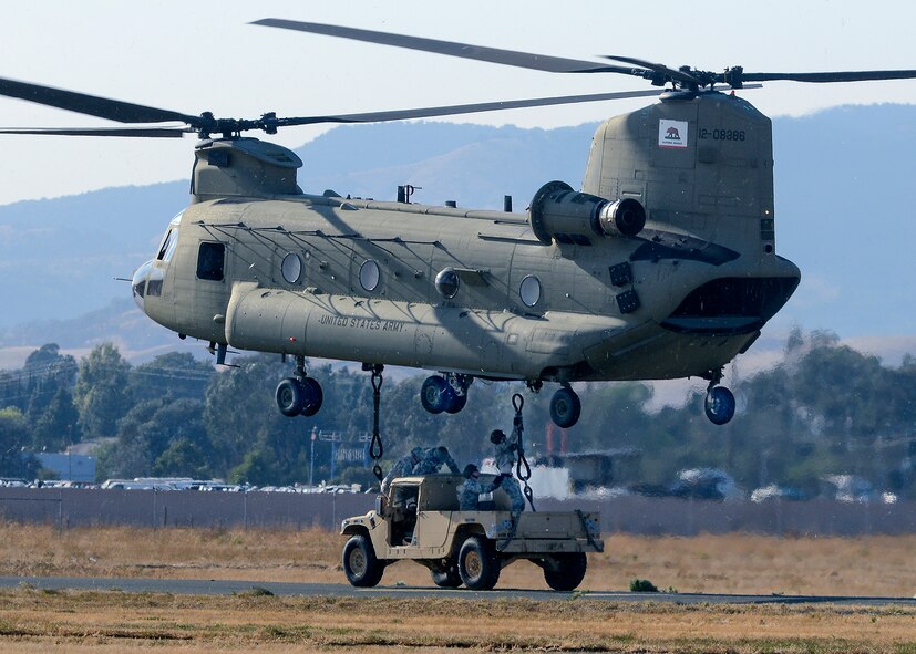 Airmen from the 60th Aerial Port Squadron and the Army National Guard's 49th Police Brigade practice loading and sling loading vehicles on a CH-47 Chinook cargo helicopter Oct. 14, 2015, at Travis Air Force Base, California. The units also practiced night time operations in total darkness with the aid of night vision goggles. (U.S. Air Force photo by T.C. Perkins Jr.)