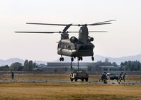 Airmen from the 60th Aerial Port Squadron and the Army National Guard's 49th Police Brigade practice loading and sling loading vehicles on a CH-47 Chinook cargo helicopter Oct. 14, 2015, at Travis Air Force Base, California. The units also practiced night time operations in total darkness with the aid of night vision goggles. (U.S. Air Force photo by T.C. Perkins Jr.)