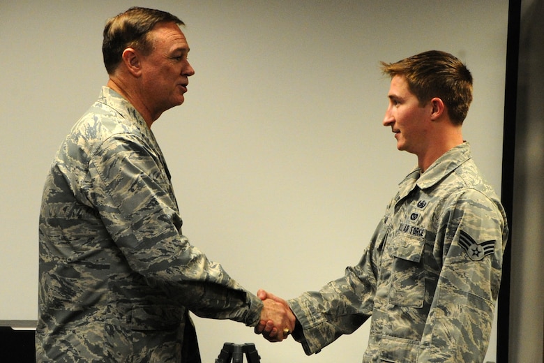 Air Force District of Washington Commander Maj. Gen. Darryl W. Burke coins SrA Drew Tesar, 11th Civil Engineer Squadron Explosive Ordnance Disposal craftsman, on Joint Base Andrews, Md., Oct. 23, 2015. Burke communicates his appreciation for the EOD Airmen’s sacrifice for the mission and recognized excellence within their career field. (U.S. Air Force photo/Staff Sgt. Matt Davis)