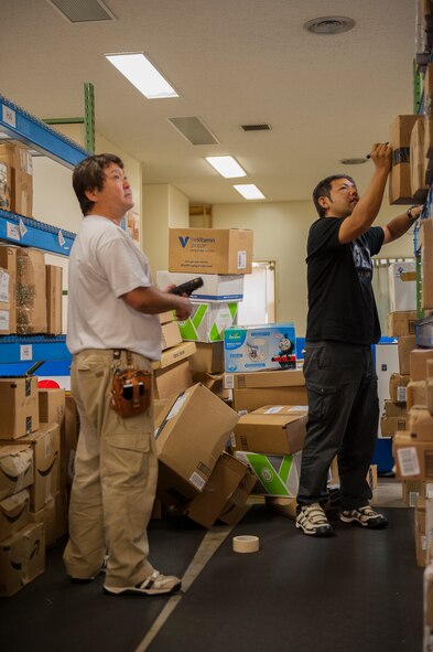 Yasuto Iha, 18th Communications Squadron postal clerk (left), assists Masahiro Iha, 18th CS postal clerk, in working through a pile of newly received packages at the Kadena Post Office Oct. 22, 2015, on Kadena Air Base, Japan. As the holidays draw closer, customers are asked to check their mailboxes daily to ensure there is room for the influx of packages expected to arrive on island over the next few months. (U.S. Air Force photo by Airman Zackary A. Henry)