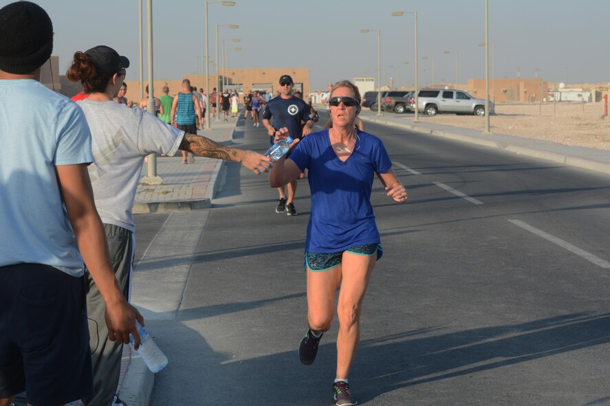 A runner taking part in the Dignity and Respect 5K grabs a water bottle near the race finish line Oct. 23, 2015 at Al Udeid Air Base, Qatar. More than 150 people took part in the race, which was organized to foster a culture of dignity and respect among service members. (U.S. Air Force photo by Tech. Sgt. James Hodgman/Released)