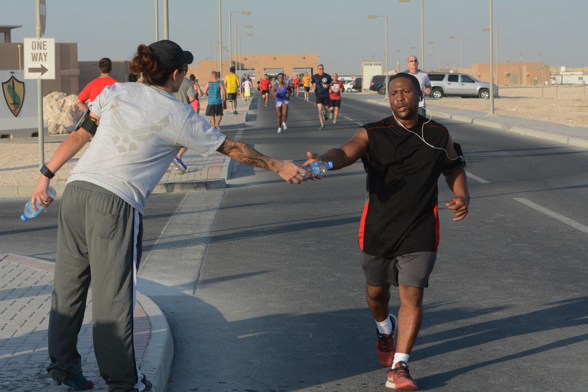 A runner taking part in the Dignity and Respect 5K grabs a water bottle near the race finish line Oct. 23, 2015 at Al Udeid Air Base, Qatar. More than 150 people took part in the race, which was organized to foster a culture of dignity and respect among service members. (U.S. Air Force photo by Tech. Sgt. James Hodgman/Released)