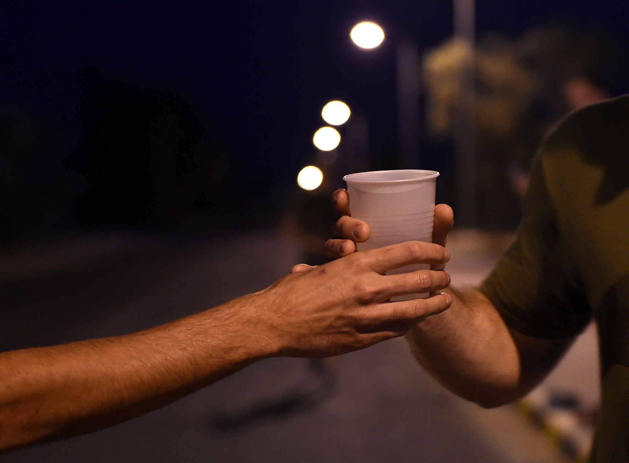 U.S. Air Force Staff Sgt. Kevin Carroll, left, hands a cup of water to Master Sgt. Mario Comella during the 40th Annual U.S. Marine Corps Marathon-Forward at an undisclosed location in Southwest Asia, Oct. 25, 2015. Runners and volunteers are currently deployed in support of Operation Inherent Resolve, which aims to degrade and defeat Daesh. (U.S. Air Force photo by Staff Sgt. Jerilyn Quintanilla/Released)   